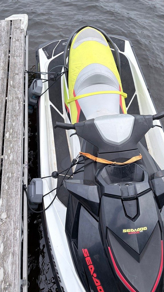 Sea-Doo jet skis tied alongside a dock with soft bumpers, seen from above